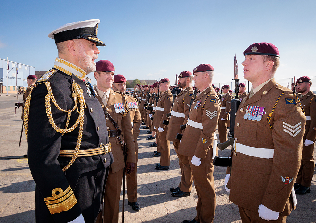 Vice Admiral Steve Moorhouse CBE walks down the open ranks of the parade in review while talking to several soldiers.